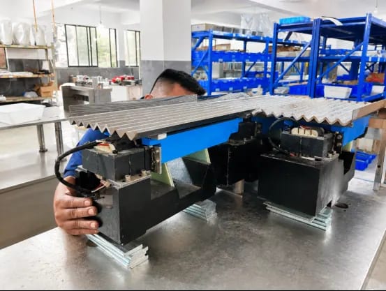 Technician working beneath a channeled feeding tray on a workshop bench